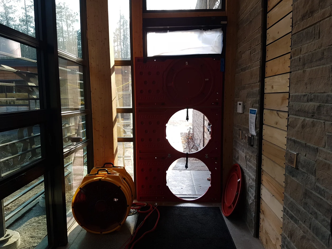 Air leakage testing equipment and a red test panel at a building entrance